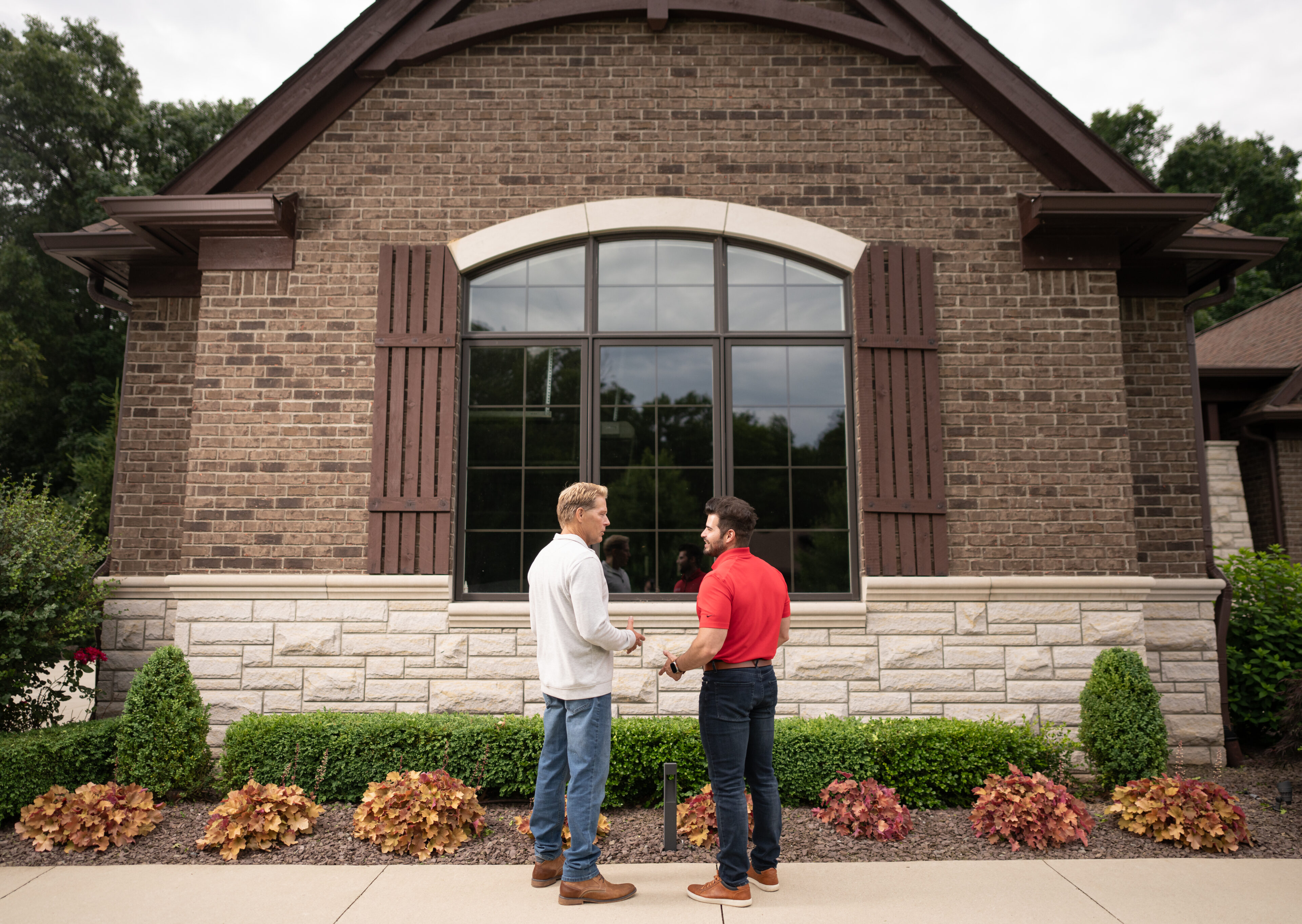 Two men outside of a home consulting about when it's time to get new windows